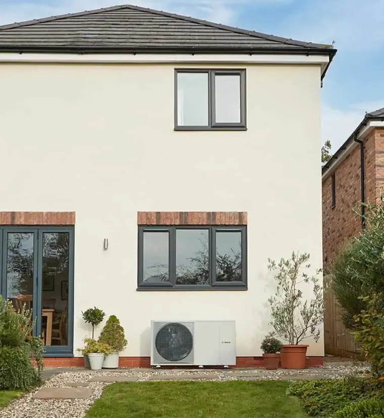 A Bosch air source heat pump fitted at the back of a two-storey house