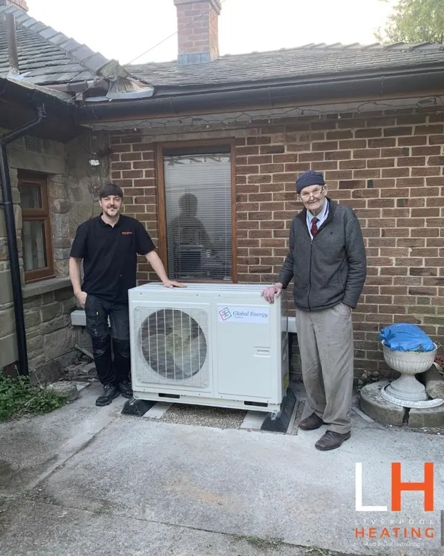 A Liverpool Heating engineer and a happy customer beside a newly fitted heat pump