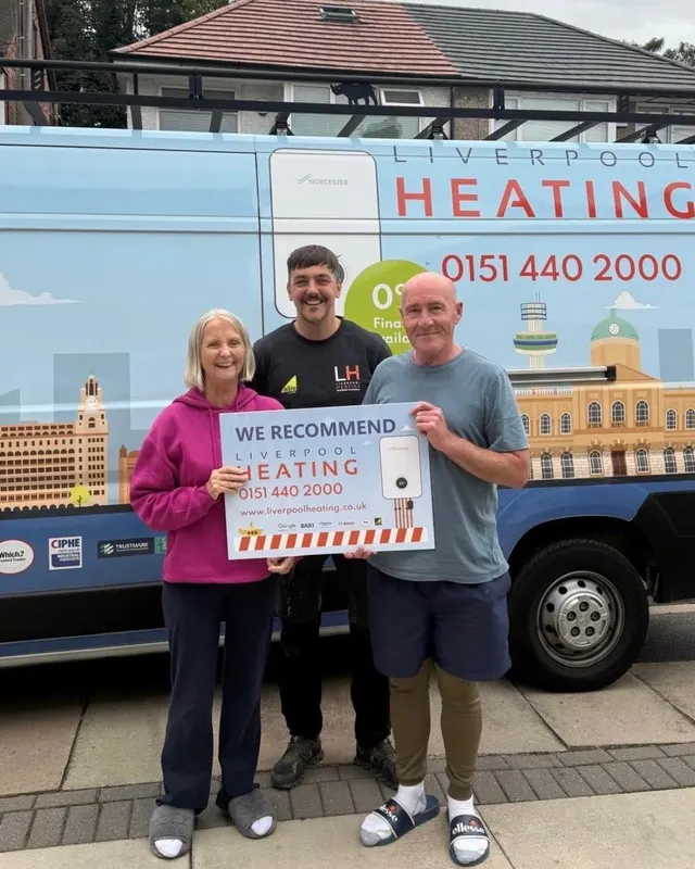 Customers with a Liverpool Heating engineer and van, holding a “We recommend” sign